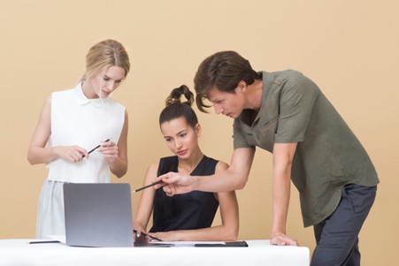 A man and two women at laptop