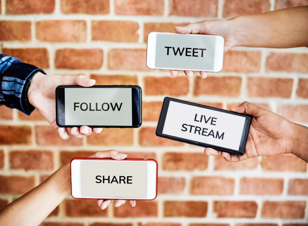 four hands with four mobile screens with text - follow, tweet, share, live stream