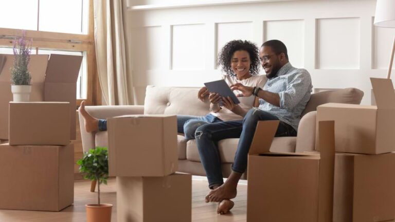 Happy couple reviews commercial roof replacement options in bright living space.